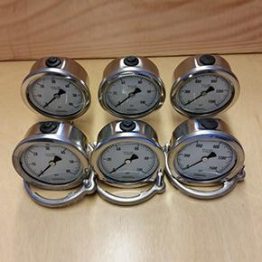 A group of six small metal clocks sitting on top of a table.